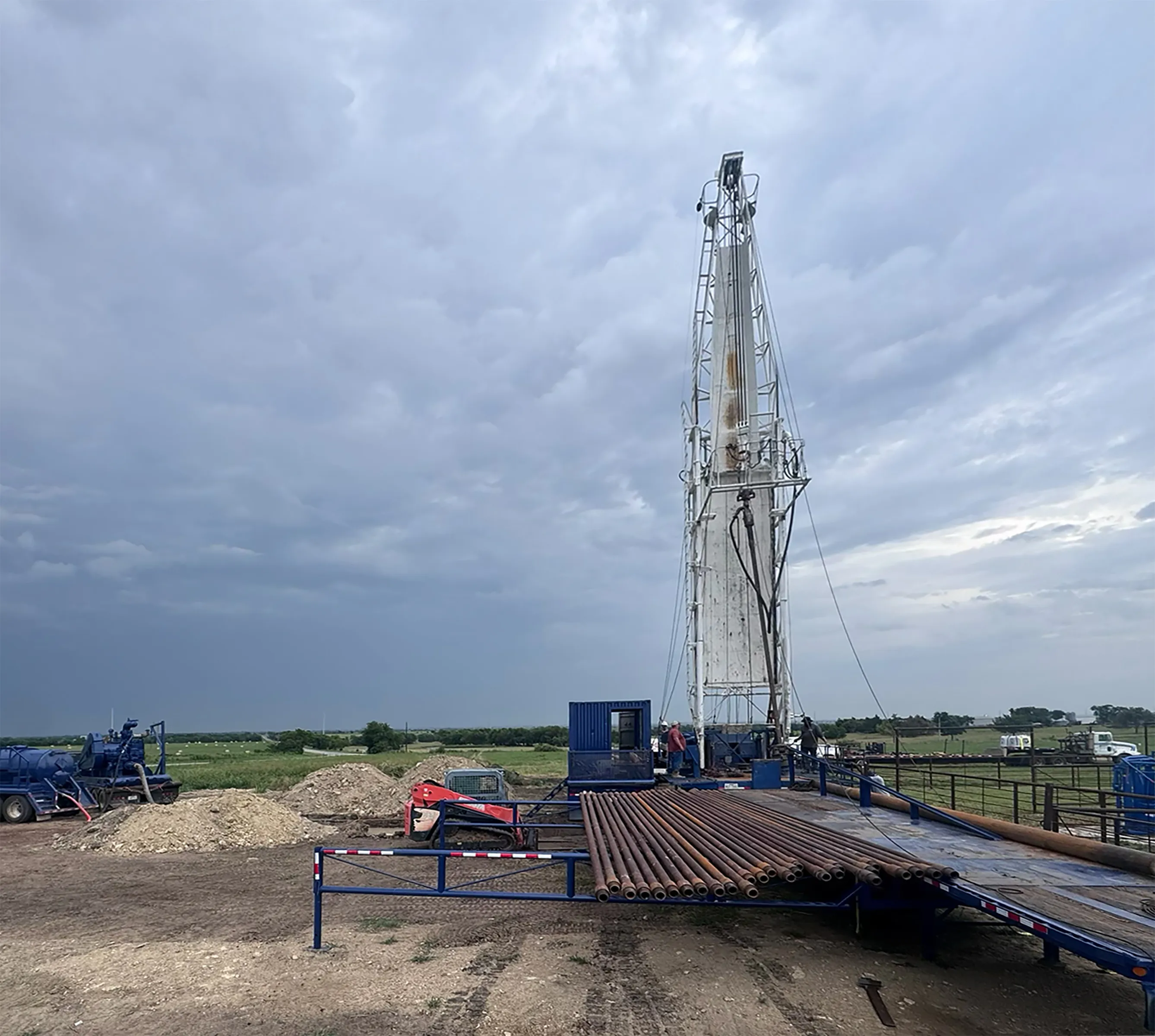 Water well drilling rig with steel casing staged on a North Texas job site